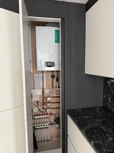 Wider view of a Vaillant boiler installation in a kitchen cupboard