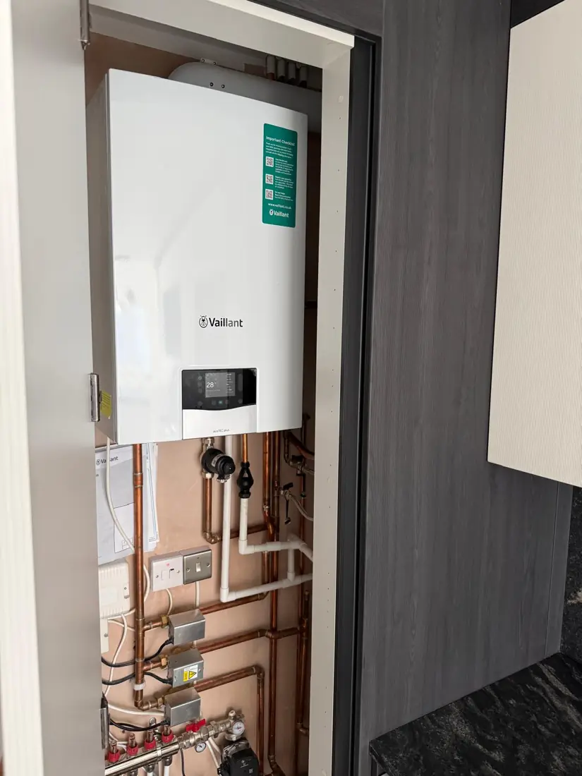 Vaillant combi boiler fitted in a kitchen cupboard with underfloor heating manifold